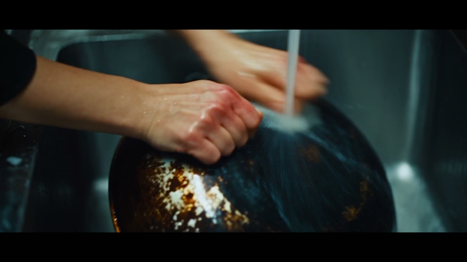 Hands washing a pot in the sink
